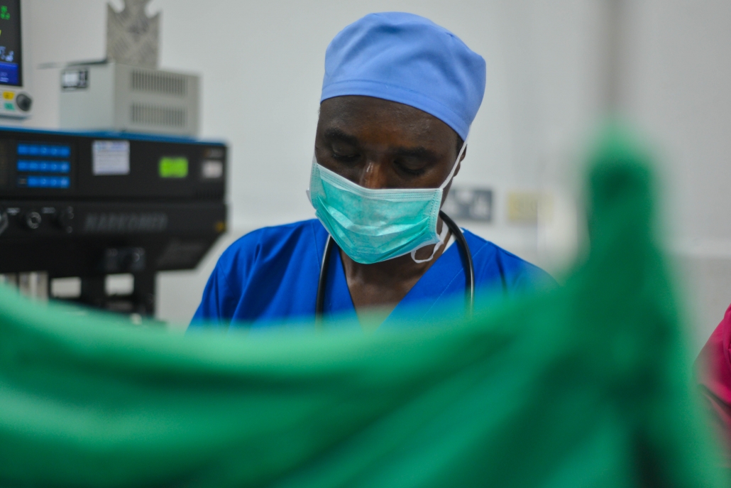 An anesthetist standing behind a surgical table curtain